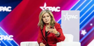 A woman in a red blazer speaking at a conference