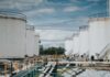 Industrial oil storage tanks with pipelines under a cloudy sky