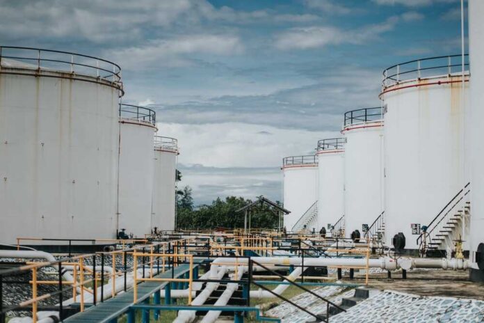 Industrial oil storage tanks with pipelines under a cloudy sky