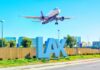 An airplane approaching LAX airport with the airport sign in the foreground