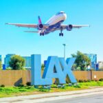 An airplane approaching LAX airport with the airport sign in the foreground