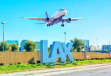 An airplane approaching LAX airport with the airport sign in the foreground