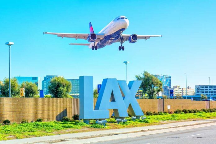 An airplane approaching LAX airport with the airport sign in the foreground