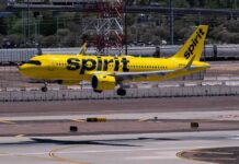 A yellow Spirit Airlines airplane landing on an airport runway