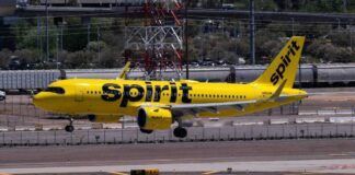A yellow Spirit Airlines airplane landing on an airport runway