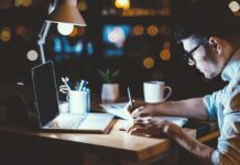 Night Owls’ Secret Heart Health Struggle Person writing notes at a desk with a laptop and a warm light