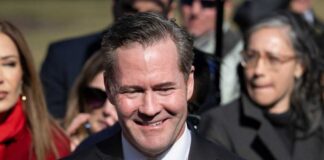 A smiling man in a suit at a political event surrounded by a crowd