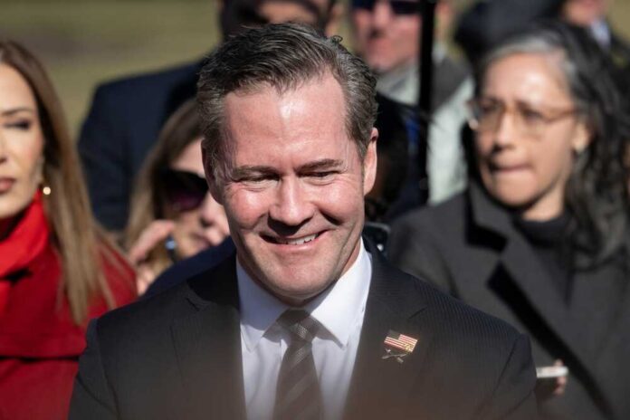 A smiling man in a suit at a political event surrounded by a crowd