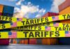 Yellow caution tape with the word 'TARIFFS' over a background of shipping containers