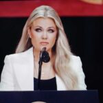 Erika Kirk’s SHOCKING No-Show – Threats Strike Again! A woman in a white blazer speaking at a podium with a microphone