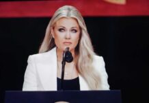 Erika Kirk’s SHOCKING No-Show – Threats Strike Again! A woman in a white blazer speaking at a podium with a microphone