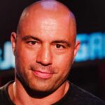 Close-up portrait of a man with a shaved head and a slight smile