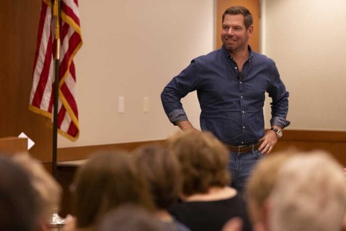 A speaker in a denim shirt engaging with an audience