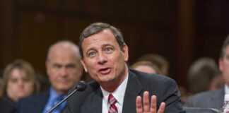 A man in a suit speaking during a formal hearing