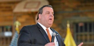 A man in a suit speaking into a microphone at an event