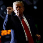 Person with raised fist in dark background.