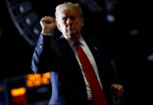 Person with raised fist in dark background.