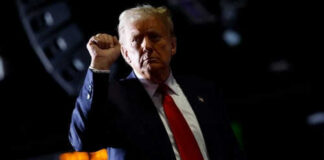 Person with raised fist in dark background.