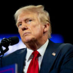 Psychiatrists VS Trump: Truth or Political Ploy? Person speaking at a microphone, wearing a suit.