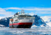 Ship navigating icy waters with snowy mountains behind