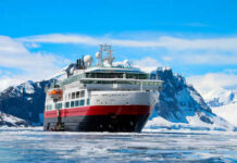 Ship navigating icy waters with snowy mountains behind