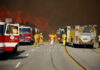 Firefighters battling large wildfire with fire trucks present