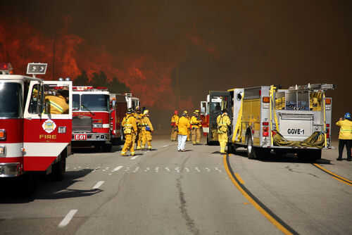 Firefighters battling large wildfire with fire trucks present
