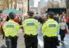 Fatal Stabbing Exposes UK Knife Law Failures Three police officers in high-visibility jackets stand facing a busy street