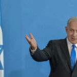 Netanyahu DEFIES Critics: Expands Lebanon Operations Man speaking next to Israeli flag.