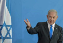 Netanyahu DEFIES Critics: Expands Lebanon Operations Man speaking next to Israeli flag.