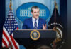 Memorial Day Uproar: Hegseth’s Bold Statement Stuns Man speaking at podium with flags in background