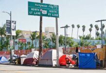 Homeless tents along a city street near a highway sign