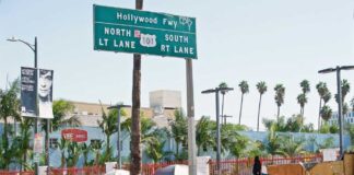 Homeless tents along a city street near a highway sign