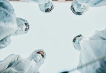 Group of medical professionals in protective gear looking down