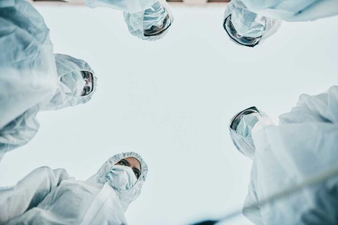 Group of medical professionals in protective gear looking down