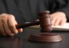 A judge's hand holding a gavel above a wooden block