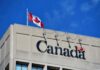 Canadian flag waving atop a building with the word 'Canada' displayed