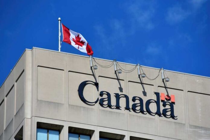 Canadian flag waving atop a building with the word 'Canada' displayed