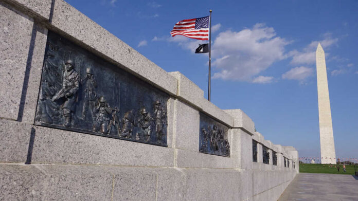 War memorial featuring bronze reliefs with soldiers and the Washington Monument in the background