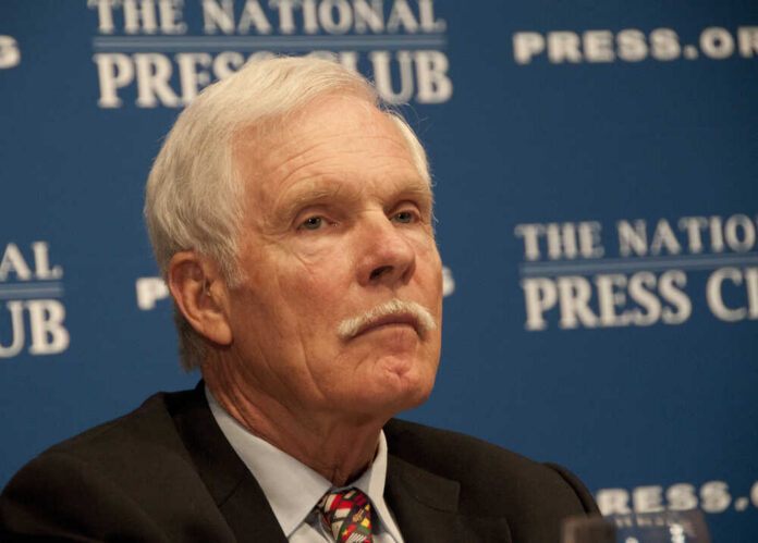 A man with gray hair and a mustache sitting at a press conference