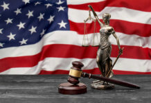 Lady Justice statue and judge’s gavel before a US flag