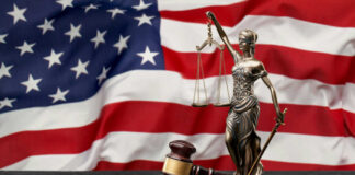 Lady Justice statue and judge’s gavel before a US flag