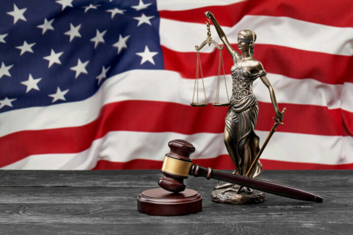 Lady Justice statue and judge’s gavel before a US flag