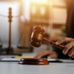 Judge's hand holding a wooden gavel above a sound block
