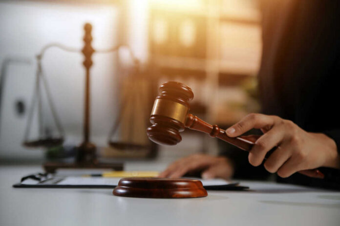 Judge's hand holding a wooden gavel above a sound block
