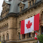 Free Speech Under Fire — Canada’s Shock Move Historic building with large Canadian flags displayed outside