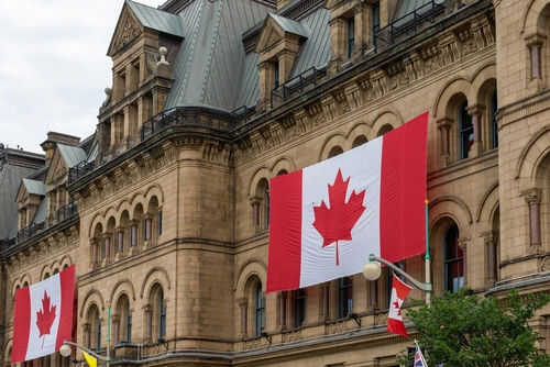 Historic building with large Canadian flags displayed outside