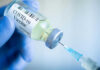 Gloved hand holding COVID19 vaccine vial and syringe