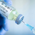 Hidden Boost: Vaccine Slashes Cardiac Danger Gloved hand holding COVID19 vaccine vial and syringe