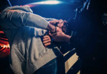 Police officer arresting a person at night.